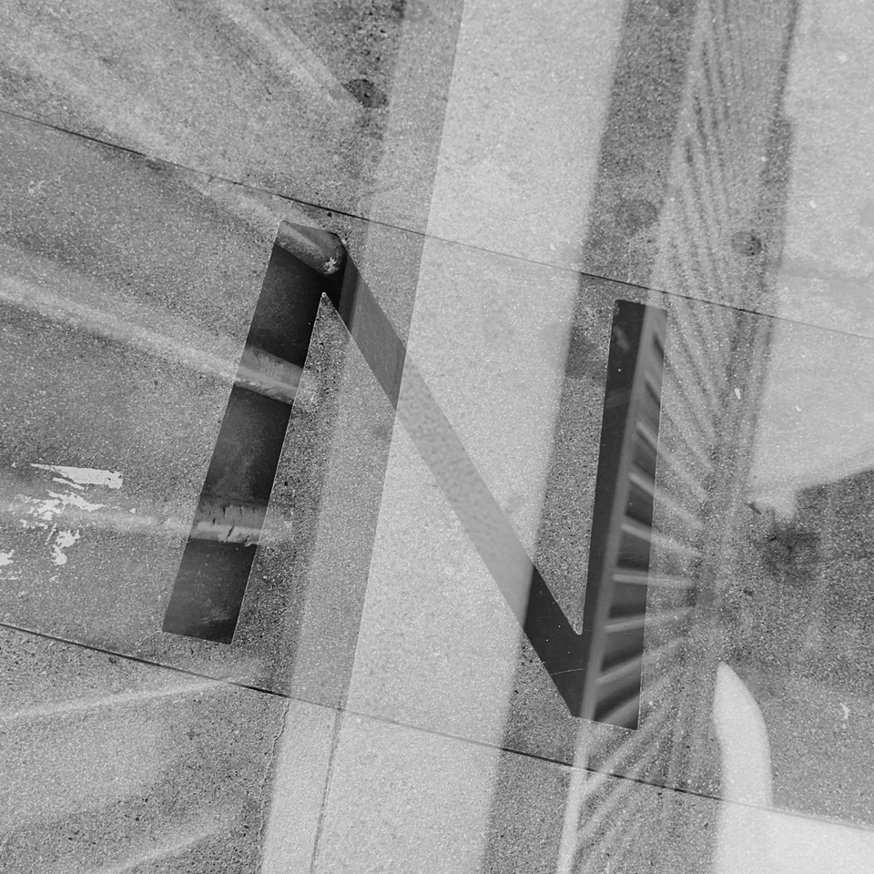 Large letters layered with vertical architectural lines in black and white.